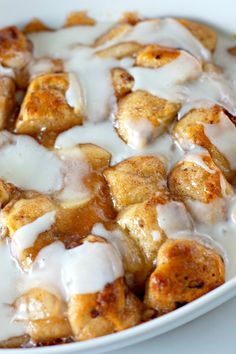 a bowl filled with cinnamon rolls covered in icing on top of a white table