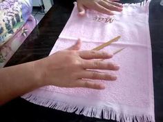 a person is holding a pencil and writing on a piece of pink paper with fringes