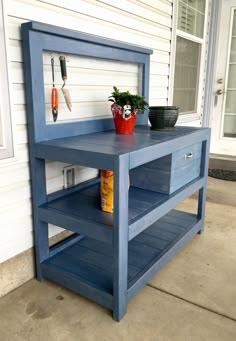 a blue shelf sitting on the side of a house next to a potted plant