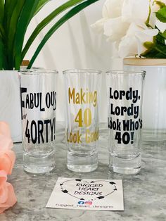 three glasses sitting on top of a table next to a pink flower and potted plant