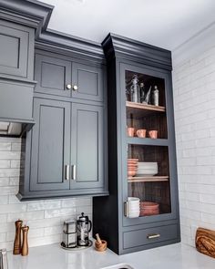 a kitchen with gray cabinets and white counter tops