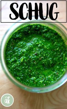 a glass jar filled with green sauce on top of a wooden table