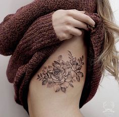 a woman with a flower tattoo on her left side ribcage is holding onto the arm