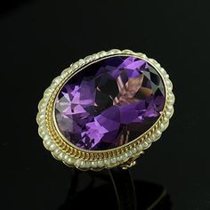 Amethyst Ring Victorian Style Cocktail Large Oval Seed Pearls Yellow Gold Bezel Set Gemstone There is nothing subtle and delicate about this ring. Flashy, expensive looking ring made of 14K yellow gold with a luxurious looking, large, oval amethyst (approximately 12ct) set in bezel and surrounded by a halo of gold twisted wire and oriental seed pearls. Sizes: 4-8 (smaller and larger sizes are available as custom orders.) PROUDLY MADE FROM SCRATCH IN NEW YORK CITY. Please allow 2-3 weeks to compl Luxury Oval Pearl Ring With Center Stone, Elegant Oval Multi-stone Amethyst Ring, Exquisite Amethyst Rings With Gemstone Accents, Exquisite Amethyst Ring With Gemstone Accents, Formal Multi-stone Oval Amethyst Ring, Elegant Amethyst Oval Cabochon Ring, Exquisite Oval Amethyst Ring For Anniversary, Formal Oval Amethyst Multi-stone Ring, Oval Multi-stone Amethyst Ring For Formal Occasions