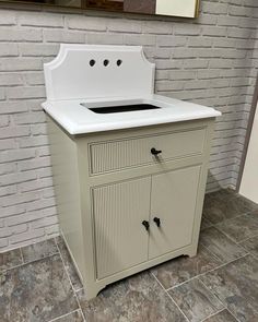 a white sink sitting on top of a wooden cabinet next to a brick wall with a mirror above it