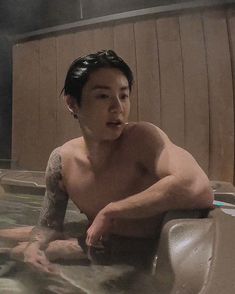 a shirtless man sitting in a hot tub with his hand on the side of him