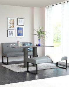 a living room with a couch, table and chair next to a plant in a vase