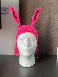 a pink knitted hat with ears on top of a mannequin's head