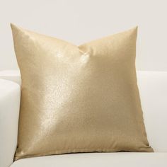 a gold pillow sitting on top of a white couch