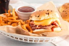 a sandwich and french fries in a basket next to some ketchup on the side