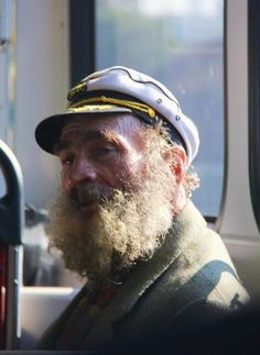 a man with a beard wearing a hat and sitting in the back of a truck