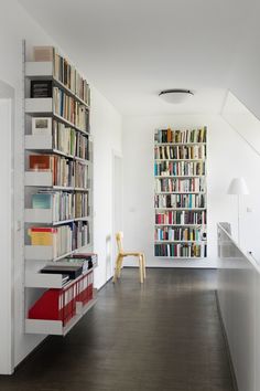 a room filled with lots of books next to a white wall