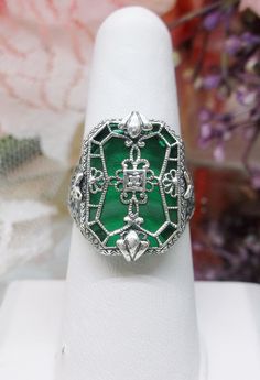 Green Camphor Glass Ring Stained Glass Design#203 Custom Made This is a lovely detailed and intricate Art Deco ring. This is lovely filigree reproduction in solid sterling silver. The verdant green glass is 18mm x 13mm. The sterling silver filigree gives the impression of a stained glass window. There is a 1mm sparkle of CZ (cubic zirconia) in the center of the filigree. The ring is 21mm North to South and 16mm East to West on the finger. The inside of the band is etched 925 for sterling silver. Camphor Glass Jewelry, Mystic Fire Topaz, Verdant Green, Intricate Art, Order Design, Glass Ring, Sterling Silver Filigree, Deco Ring, Glass Rings