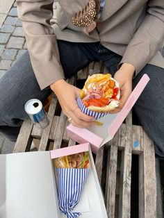 a person sitting on a bench with some food in their hands