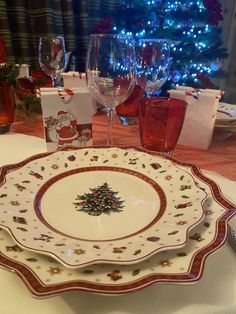 a plate with a christmas tree on it sitting on a table next to wine glasses