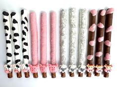 five different types of candy sticks with animals on them, all decorated in pink and white