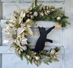 a christmas wreath with a cat on it and ornaments hanging from the front door,