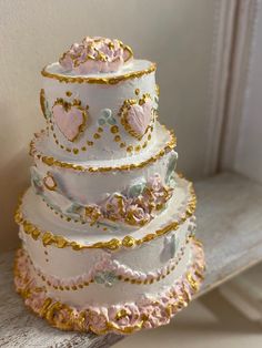 a three tiered wedding cake with hearts on it