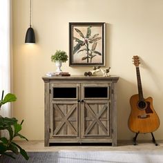 a wooden cabinet sitting next to a plant and a guitar on top of a rug