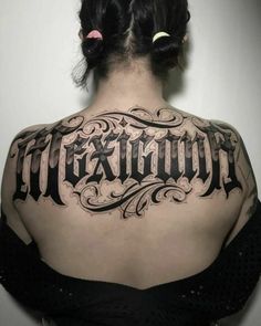 the back of a woman's shoulder with an old english tattoo design on it