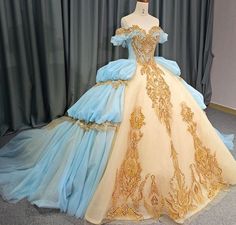 This unique Quinceañera dress is crafted with luxurious details; a soft, ethereal baby blue hue is complemented by golden accents and a voluminous gown-style skirt. A lace accented bodice with a sweetheart neckline is offset by off-the-shoulder cuff sleeves and a majestic train adorned with ornate lace. To complete the look, the back is designed with an adjustable satin ribbon lace-up closure. material: organza, tulle, lace color: as shown type: party ball gown sweetheart neckline lace up back t Gaun Abad Pertengahan, Old Fashion Dresses, Fantasy Dresses, Princess Ball Gowns, Fantasy Gowns, فستان سهرة, Fairytale Dress, Quince Dresses, Fantasy Dress