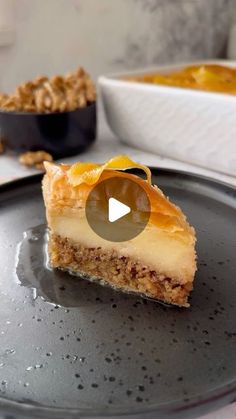 a piece of cheesecake sitting on top of a metal plate next to a bowl of nuts