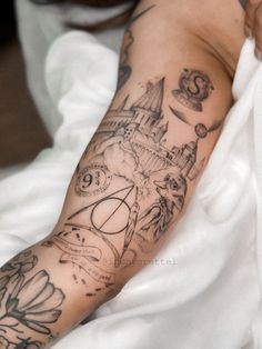 a woman's arm with tattoos on it and an image of a castle in the background