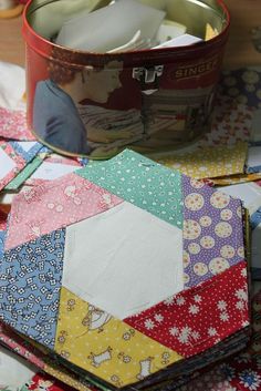 a table topped with lots of different types of quilts and other fabric items next to a vase filled with flowers