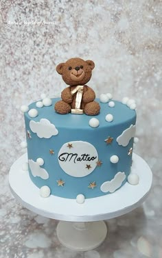 a teddy bear sitting on top of a blue and white cake with stars around it