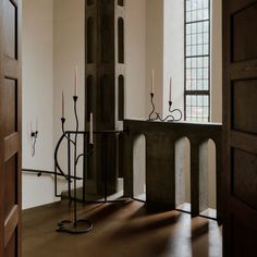 a room with some candles on the table and two windows in the wall behind it