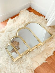 a mirror sitting on top of a wooden floor next to a white rug with a gold frame