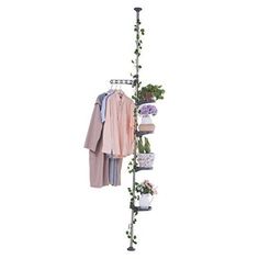 a coat rack with clothes hanging from it's sides and plants growing on top