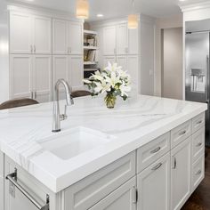 a large kitchen with white cabinets and marble counter tops