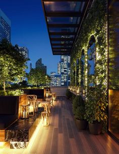 an outdoor dining area at night with lights on the tables and plants growing in pots