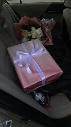 a pink wrapped gift sitting in the back seat of a car with flowers on it