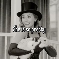 a woman wearing a top hat and gloves holding a small cat in her hands with the caption she is so pretty