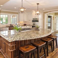 a large kitchen with an island in the middle of it and stools at the end