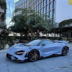 a blue sports car parked in front of a tall building