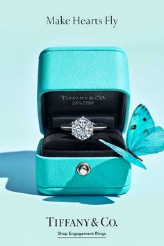 the tiffany & co engagement ring is in its blue box with a butterfly on it