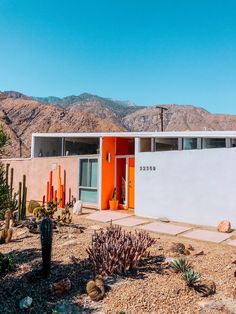 an orange and white house in the desert with mountains in the background