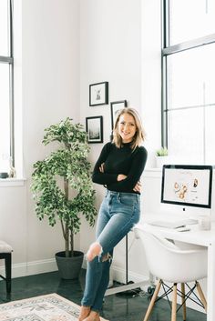 a woman sitting on top of a chair in front of a desk with a computer