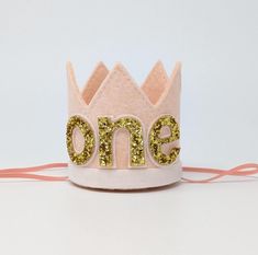 BLUSH Felt Crown, WHITE glitter trim, with or without GOLD glitter number.   Our party hats and crowns are attached to a comfortable elastic and meant to be worn around the back of the head, behind the ears. Tilt to the side for a fun, whimsical look! LITTLE BLUE OLIVE SHOP CROWNS and HATS are the perfect accessory for birthday celebrations, memorable photo shoots and every day fun for dress up. Hats are hand crafted of a high quality, non-shed glitter made and imported from Europe. Adjustable Pink Crown With Round Shape, Cute Birthday Crown With Round Shape, Adjustable Princess Crown For Party, Adjustable Mini Hats With Round Crown For Birthday, Adjustable Mini Hats With Round Crown For Birthdays, Adjustable Round Crown Mini Hats For Birthday, Adjustable Round Crown For Birthday, Gold Birthday Crown With Tall Shape, Gold Tall Crown For Birthday