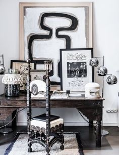 a black and white desk with some pictures on the wall next to it in front of a painting