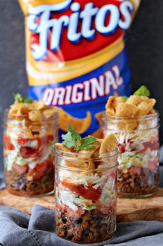 three mason jars filled with taco salad and chips