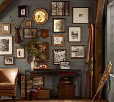 a room filled with lots of framed pictures on the wall next to a brown chair