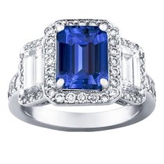 a blue and white diamond ring with two baguets on the side, surrounded by diamonds