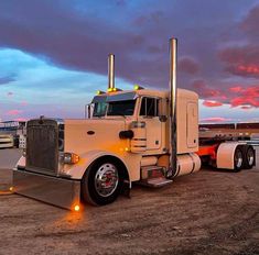 a large semi truck parked on top of a dirt field