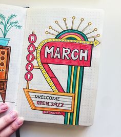 a hand is holding an open notebook with the word march on it and a drawing of a welcome sign