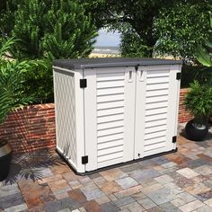 a large white storage container sitting on top of a brick patio next to trees and bushes