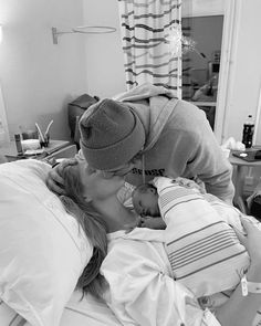 a woman in a hospital bed kissing a baby